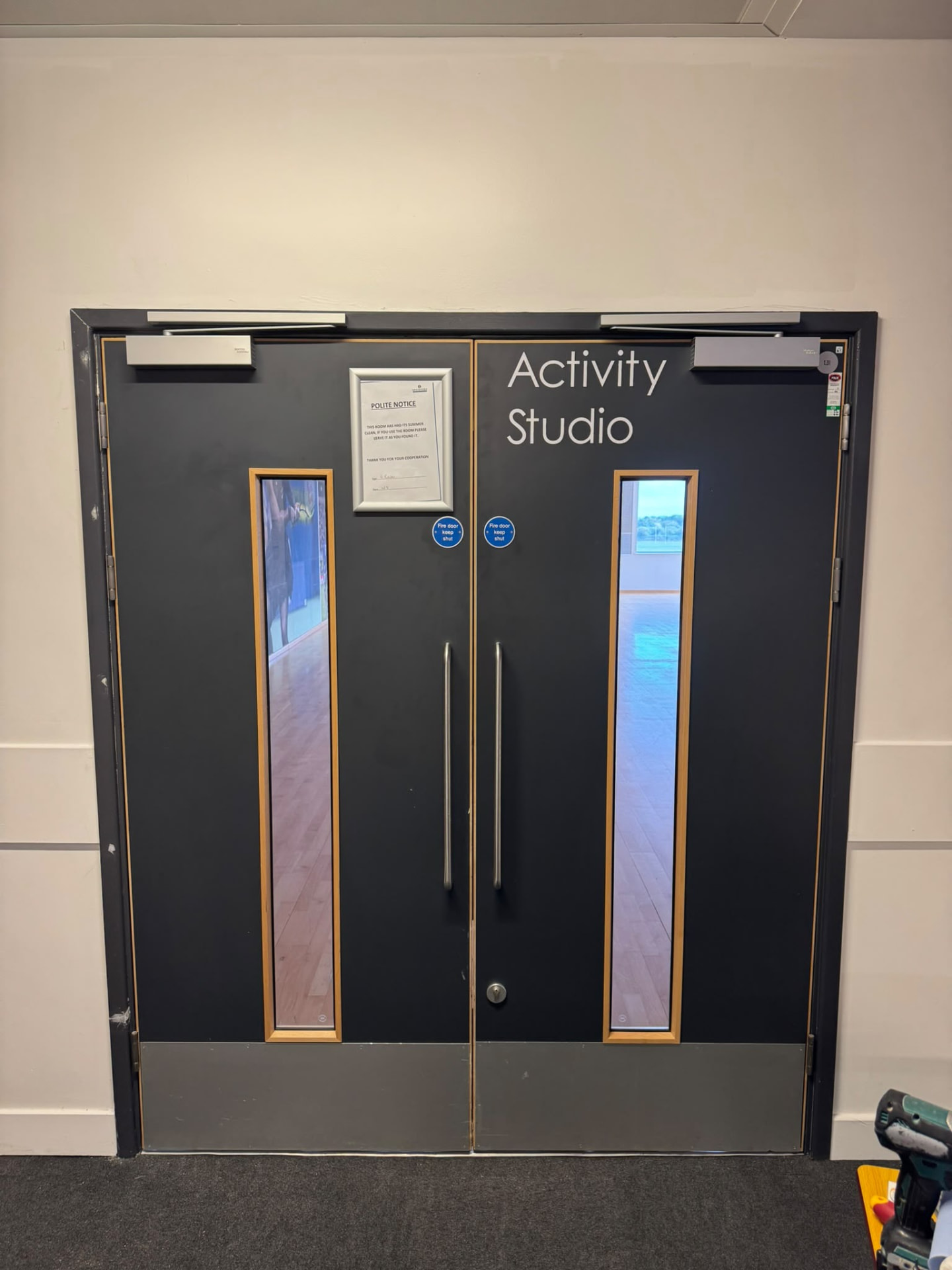 Double fire doors with tall vision panels and pull handles, school activity studio